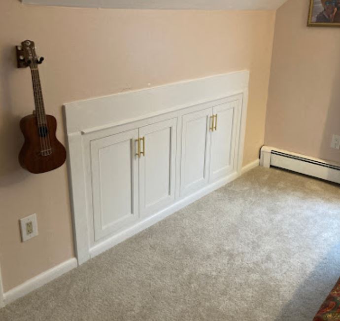 classic acoustic guitar hanging on a wooden wall and wooden closed cabinets in a bedroom