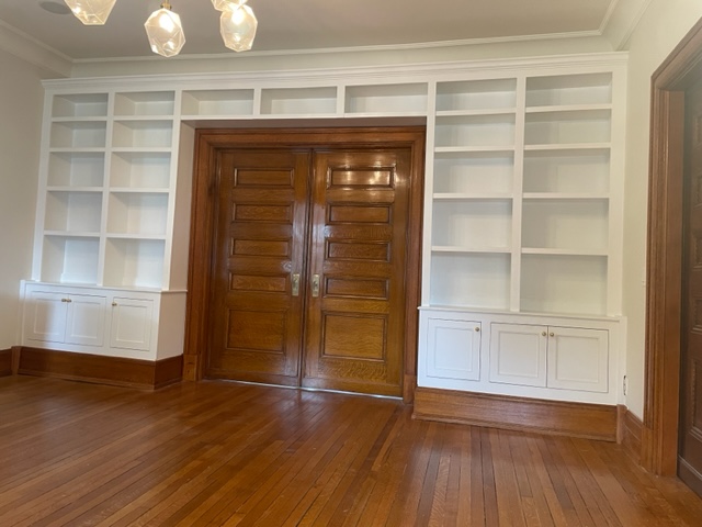 Room with door and light colored wooden shelves